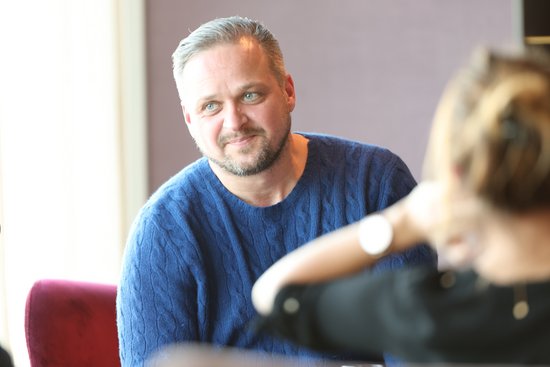 Mann mit blauem Pullover und kurzem Bart blickt lächelnd eine Frau mit hochgestecktem Haar an.